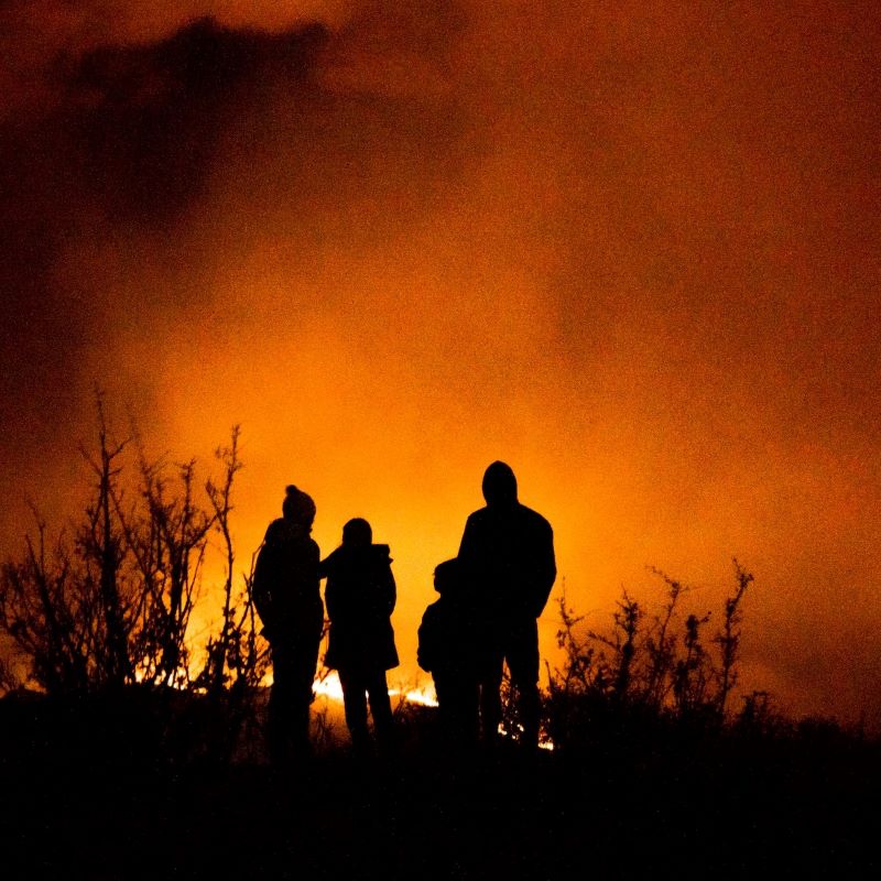 Family in the shadows. A safe distance away. Peering out over uncontrolled wildfire.