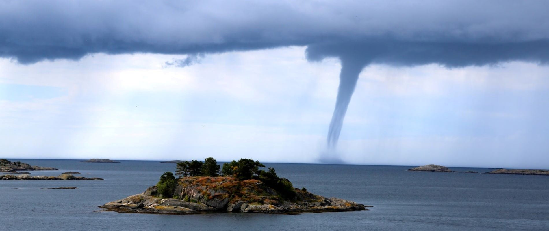Natural Disaster Waterspout Tornado approaching Island and mainland in daytime..