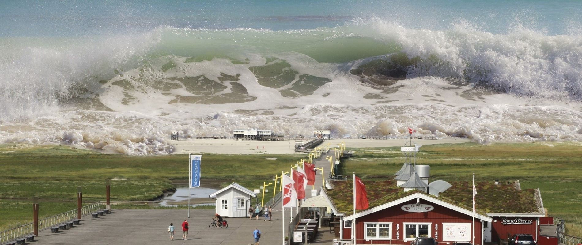 Aerial photo of inbound tsunami seaquake wave across grass field, red building, and seaside beach huts. St Peter-Ording, Germany 2016